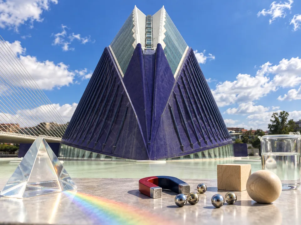 Ilustración generada con IA: exterior de CaixaForum València con una sutil refracción de luz, un imán y piezas sencillas de experimentos científicos.