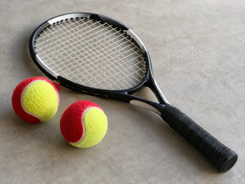 AI-generated illustration: A small tennis racket and red-and-yellow tennis balls.