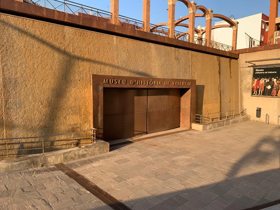 Entrance and brick arches of Museu d'Història de València in warm evening light.